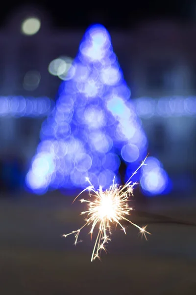 Odaklanamayan yılbaşı ağacı mavi ışıklar parlıyor ve arka planda maytaplar var..