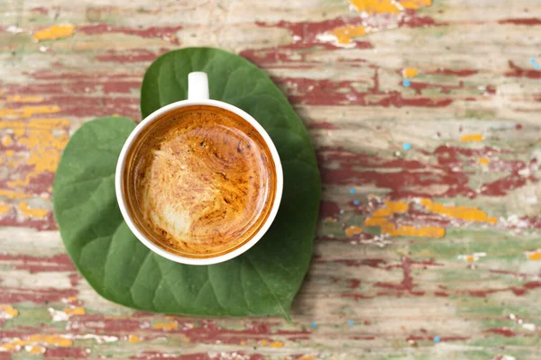 Güzel yeşil yapraklı taze bir fincan koyu kahve sabahı çok daha iyi yapar. Üst görünüm.