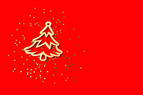 Kırmızı arka planda ahşap Noel dekoru. Konfetideki ahşap Noel ağacı. Üst görünüm.