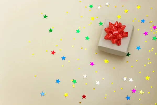 Mevcut kutu ve pastel arka planda yıldız konfetisi. Noel ve tatil konsepti için düz konulu kompozisyon. Metin için yer.