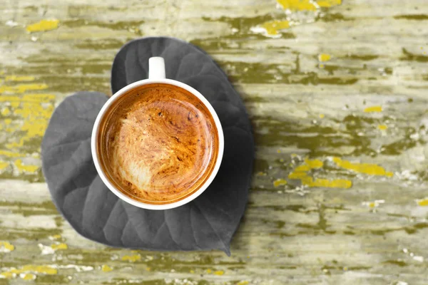 Güzel yeşil yapraklı taze bir fincan koyu kahve sabahı çok daha iyi yapar. Üst görünüm.