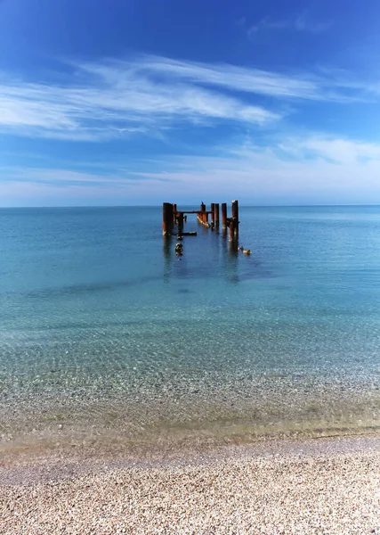 Denizde eski bir rıhtımın kalıntıları. Yaz gününde temiz sıcak su. Mükemmel yaz manzarası.