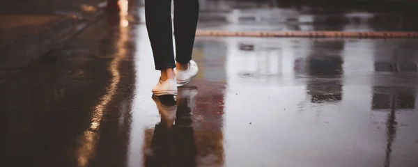 Yağmur fırtınasından dolayı ıslak beton yol yağarken sokakta uzun süre yürüyen tanınmayan bir kadın. Gece şehir merkezindeki caddeye bir kadın ayak basıyor..
