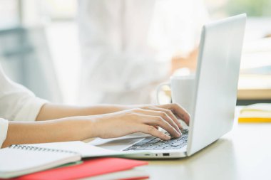 Ofiste çalışan bir kadın kişisel dizüstü bilgisayarını kullanarak bilgisayarın klavyesini kapatıyor. Ofis kadını e-posta ve sosyal medya göndermek için dizüstü bilgisayar kullanıyor.