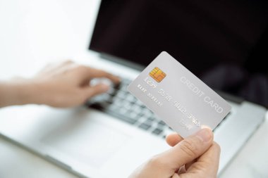 Online alışveriş ve güvenli online ödeme konsepti dizüstü bilgisayar ekranının önünde kredi kartı tutan tanınmayan bir kadın.