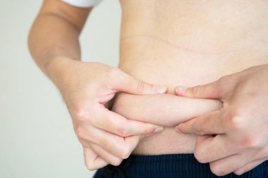 Şişman karnına yapışan tanınmayacak kadar şişman bir adam sağlıksız beslenme davranışlarından dolayı aşırı kilolu bir adam. Koca ve ağır bir göbek..