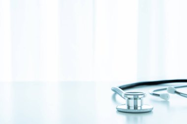Profesyonel tıbbi steteskop beyaz masada. Telif alanı ile yakın plan. Doktorun steteskobu, beyaz masa arkasında kalp atışlarını dinlemek için kulaklık..