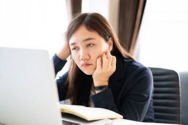 Ofiste çalışan Asyalı stresli iş kadını acı çekiyor ve mutsuz. Kadın ofiste çalışırken rahatsız oluyor, kadın işinden dolayı acı çekiyor. Kız çok çalışıyor diye endişeleniyor..