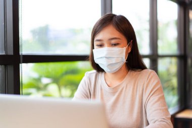 Mutlu Asyalı kadın, dizüstü bilgisayar kullanarak kahve dükkanında çalışıyordu. Kendine güvenen Asyalı kız internette ve sosyal ağda gezinmek için güzel gülüşlü dizüstü bilgisayar kullanıyor..