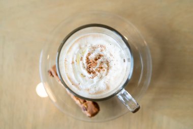 Viyana kahvesi kahvenin üstüne krema serpilmiş ve üzerine tarçın dökülmüş. Öğleden sonra sehpanın üstünde Viyana kahvesi ve çikolata çubuğu var..