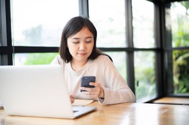 Kafede çalışan Asyalı mutlu bir kadın ya da dizüstü bilgisayarda ortak çalışma alanı, online çalışma ve online video konferans konsepti modern iş hayatı tarzında. Asyalı işkadını gülümseyen portre.