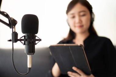 Mutlu Asyalı kadın evinde podcast stüdyosu için bir oturma odası kuruyor, evinde bir podcast ve online radyo istasyonu düzenleyen bir kadın. Profesyonel genç podcaster mikrofon aracılığıyla konuşuyor..