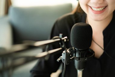 Mutlu Asyalı kadın evinde podcast stüdyosu için bir oturma odası kuruyor, evinde bir podcast ve online radyo istasyonu düzenleyen bir kadın. Profesyonel genç podcaster mikrofon aracılığıyla konuşuyor..