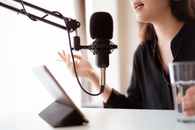 Güzel ve yakışıklı Asyalı kadın podcast kanalını düzenliyor. İş kadını internetteki yayını için bilgisayarından ve tabletinden canlı yayın yapıyor. Modern çalışma tarzı