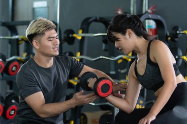 Ağırlık eğitmeni kas geliştirme için acemi çırağı eğitir. Fitness kişisel antrenörü fiziksel egzersiz için bir kadına tavsiye.