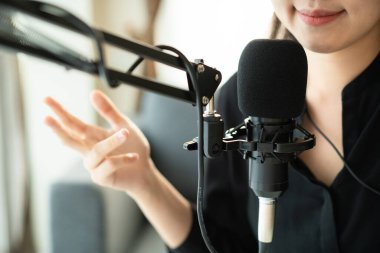Güzel ve yakışıklı Asyalı kadın podcast kanalını düzenliyor. İş kadını internetteki yayını için bilgisayarından ve tabletinden canlı yayın yapıyor. Modern çalışma tarzı