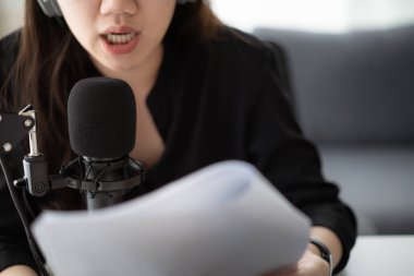 Güzel ve yakışıklı Asyalı kadın podcast kanalını düzenliyor. İş kadını internetteki yayını için bilgisayarından ve tabletinden canlı yayın yapıyor. Modern çalışma tarzı
