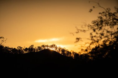 Dağ perdesinin arkasında güzel, siluetli gün batımı. Yaklaş. Huzurlu bir gün batımı ya da güzel dağ ve ormanın üzerinde gün doğumu - telif uzayı ile zirve.
