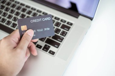 İnternetten alışveriş yapmak için kredi kartı kullanan tanınmamış Asyalı genç bir adam. Adam online ödemede kredi kartı kullanıyor. E-ticaret yoluyla modern alışveriş tarzı.