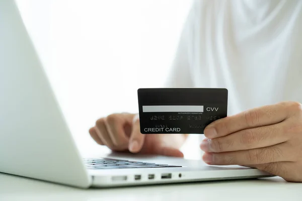 Unrecognizable Asian young man using a credit card for making a purchase on the internet. Man use a credit card in online payment. Modern shopping lifestyle via e-commerce.