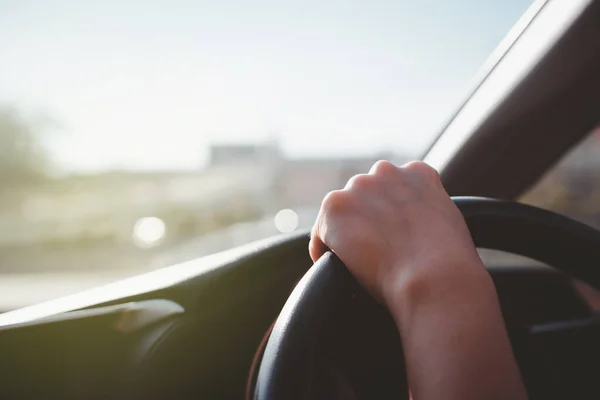 Woman driving a car and catching on the steering wheel at 12 o\'clock position with copy space. Woman driving a long the highway during the day, serious driving woman.