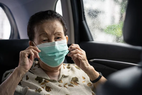 Very old Asian woman age between 80 -90 years old travel by the personal car, elder woman using protective face mask during traveling. Coronavirus or COVID-19 pandemic concept. COVID19 outbreak.