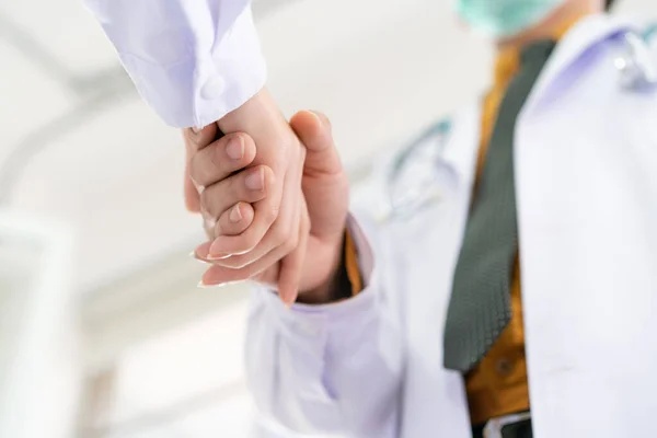Two senior specialist doctor making a handshake together, trust and good teamwork in medical service in hospital. Concept of collaborative medical partnership in medical service and enterprise.