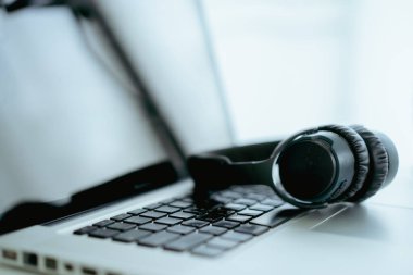 Bilgisayarda kopyalanmış kulaklıklı modern bir kulaklık var. Kulaklıklar kişisel defter bilgisayarında. Modern ses kayıt stüdyosu ve online radyo istasyonu. Canlı sesli buharlı ekipman.