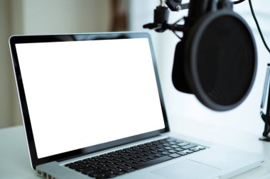 Ses kayıt stüdyosuna klipsleme yolu kurulmuş boş bir ekran ile Mockup laptop bilgisayar. Canlı buhar ve podcast internet radyo stüdyosu.