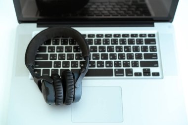 Bilgisayarda kopyalanmış kablosuz kulaklık bırakılmış. Kulaklıklar kişisel defter bilgisayarında. İşten sonra rahatlama.