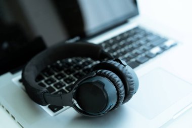 Bilgisayarda kopyalanmış kablosuz kulaklık bırakılmış. Kulaklıklar kişisel defter bilgisayarında. İşten sonra rahatlama.