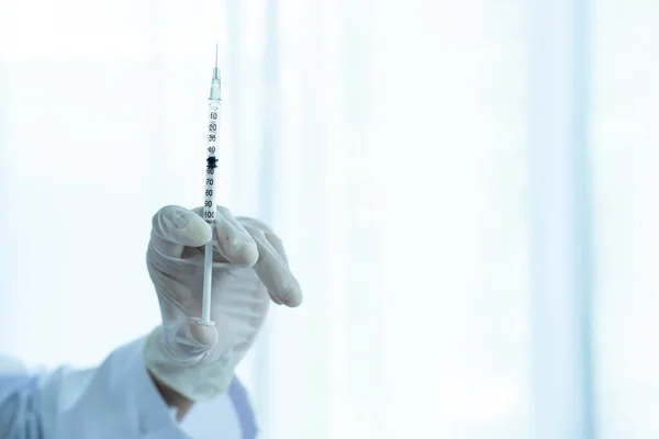 Doctor preparing a dose of vaccine for injection at patient left arm close up with copyspace. Healthcare and medical service concept. COVID-19 or coronavirus cure vaccine injection.