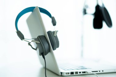 Bilgisayarda kopyalanmış kulaklıklı modern bir kulaklık var. Kulaklıklar kişisel defter bilgisayarında. Modern ses kayıt stüdyosu ve online radyo istasyonu. Canlı sesli buharlı ekipman.
