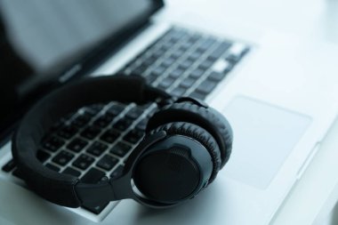 Bilgisayarda kopyalanmış kablosuz kulaklık bırakılmış. Kulaklıklar kişisel defter bilgisayarında. İşten sonra rahatlama.