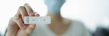 Hijyen koruyucu yüz maskesi takan Asyalı genç bir kadın SARS 2019-nCoV COVID-19 Coronavirus antijen hızlı test kiti kullanıyor. Evde tarımsal test kiti. COVID-19 antijen hızlı testi.