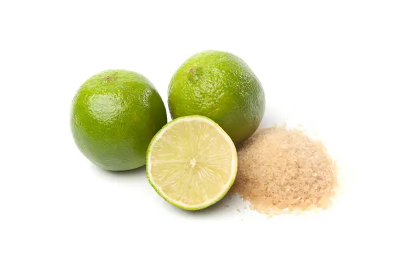 Limes verdi e zucchero greggio su bianco — Foto Stock