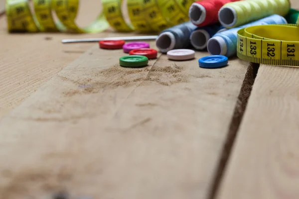 Botones, hilos y cinta adhesiva para la costura sobre fondo de madera —  Fotos de Stock