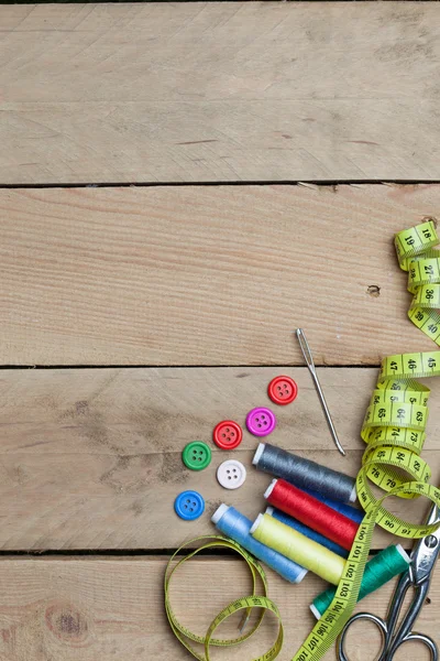 Buttons, threads and tape for needlework on wood background — Stock Photo, Image