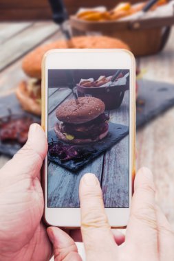 El ile akıllı telefon, hamburger gıda resim çekmek
