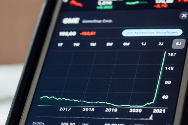 BERLIN, GERMANY - JANUARY 29, 2021: Close up to chart of GameStop stock hype amongst fight between small investors organized through Reddit and hege funds on the screen of an iPhone 7 Plus with personalized background.