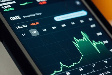 BERLIN, GERMANY - JANUARY 29, 2021: Close up to chart of GameStop stock hype amongst fight between small investors organized through Reddit and hege funds on the screen of an iPhone 7 Plus with personalized background.