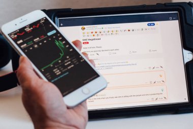 BERLIN, GERMANY - JANUARY 31, 2021: Close up to GameStop stock exchange chart with Reddit social media discussion platform in background on iPad