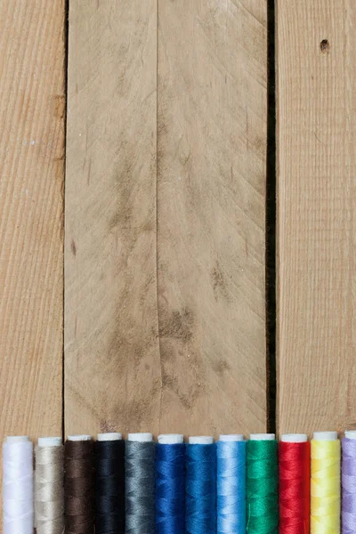 Барвисті нитки на дерев'яному фоні — стокове фото