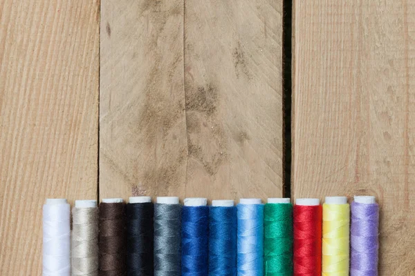 Colorful thread spools on wooden background — Stock Photo, Image