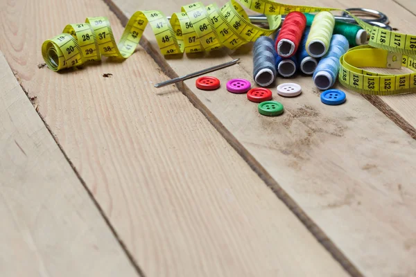 Botones, hilos y cinta adhesiva para la costura sobre fondo de madera —  Fotos de Stock