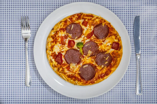 Pizza Salami com talheres em pano de mesa xadrez azul — Fotografia de Stock