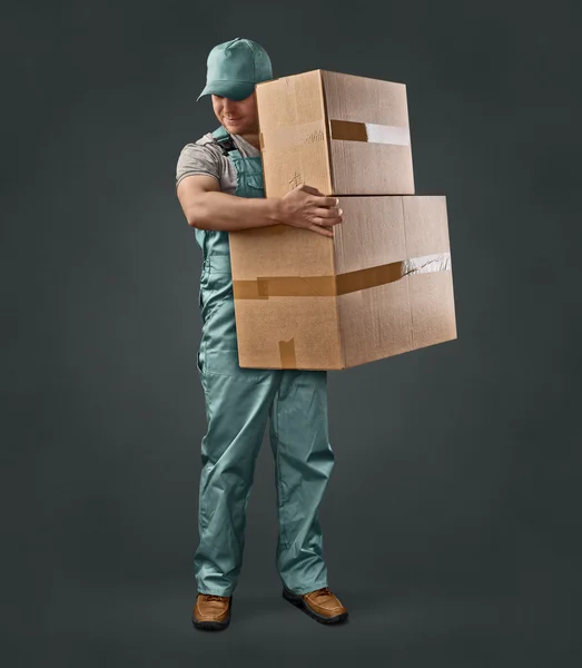 Delivery man in green uniform holding a box — Stock Photo, Image