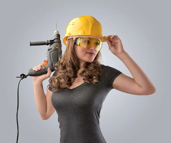 Chica trabajadora en un casco con un taladro — Foto de Stock