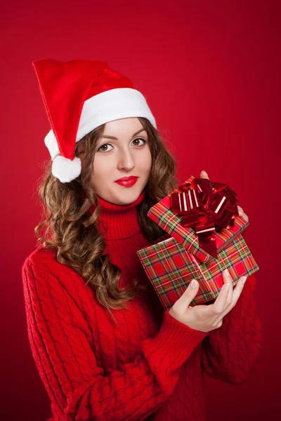 Ragazza in maglione rosso che tiene il regalo di Natale indossando Santa Clau — Foto Stock