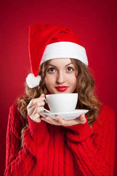 Beautiful brunette girl in Santa Clause hat holding white mug — Stock Photo, Image